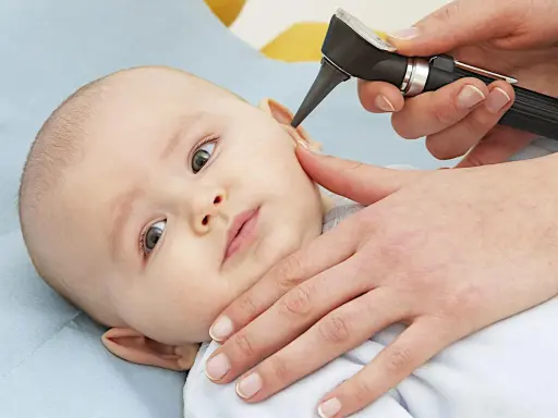 Esame dell'orecchio di un neonato per diagnosticare un'otite.