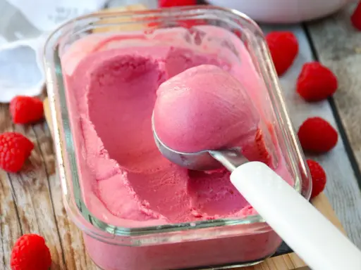 Glace framboise sans sorbetière, on dirait qu'elle est faite avec du lait concentré. Une boule est prélevée avec une cuillère.