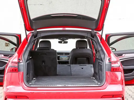 Czerwone Audi A6 Avant z otwartą klapą bagażnika i drzwiami. Wnętrze pokazuje przestronny bagażnik, idealny na wakacyjne wyjazdy, z możliwością powiększenia przestrzeni po złożeniu siedzeń.