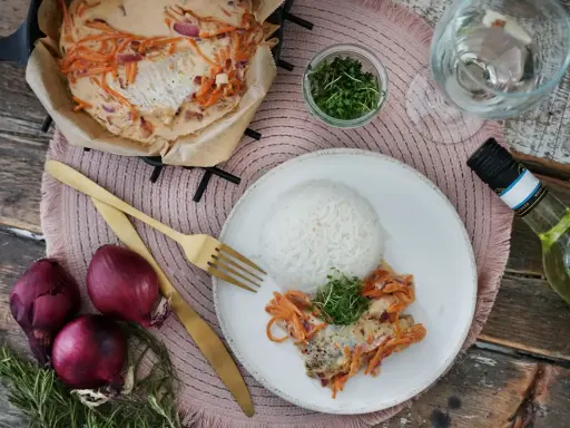 Ein Rotbarschfilet mit Senfsauce, serviert mit Reis und garniert mit Kresse. Dazu passen rote Zwiebeln und ein Glas Weißwein.