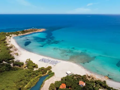 Spiaggia bianca e mare cristallino in Sardegna, ideale per villaggi per famiglie.