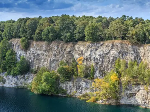 Skałki Twardowskiego w Krakowie, z malowniczym kamieniołomem i turkusową wodą, otoczone bujną zielenią drzew.