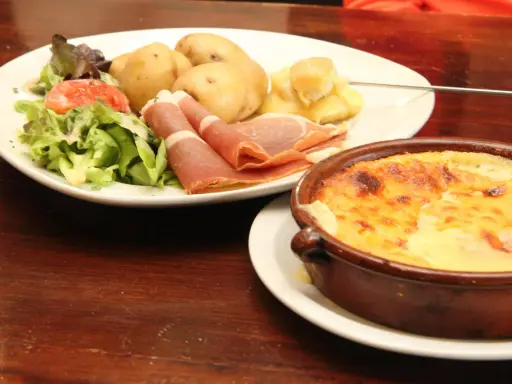 Un plat de spécialité auvergnate : pommes de terre, jambon cru, salade et un gratin de fromage fondant.