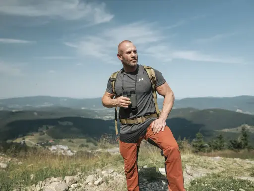 Mężczyzna w letnim stroju górskim: koszulka, spodnie trekkingowe i plecak. Idealny przykład, jak się ubrać w góry latem.