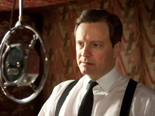 Colin Firth i en vit skjorta med hängslen och slips, nära en mikrofon. En scen från filmer och tv-program med Colin Firth.