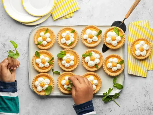 Douces tartelettes à l'abricot, décorées de crème fouettée et de menthe, prêtes à être dégustées.