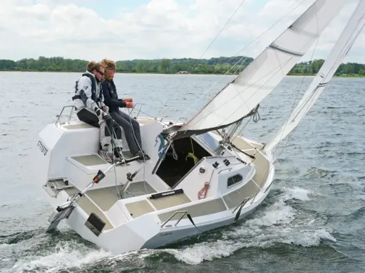 Zwei Segler genießen eine Fahrt auf einer Sailart 20. Das Boot gleitet durch das Wasser, die Segel sind gesetzt.
