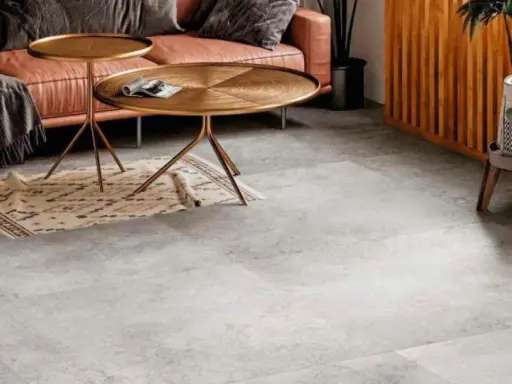 Un elegante soggiorno con divano in pelle color caramello, tavolini dorati e un tappeto etnico su un **pavimento grigio** che crea **abbinamenti** moderni e sofisticati.