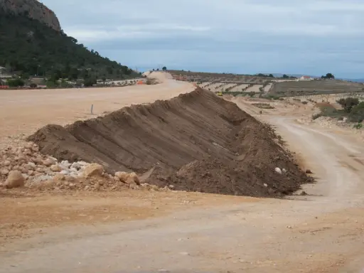 Un terraplén, parte de una obra vial, se eleva con tierra removida. El terraplén significado es la elevación artificial del terreno.