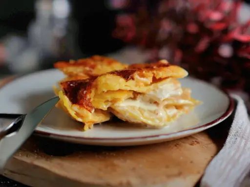 Ein Stück cremiges Kartoffelgratin mit goldbrauner Kruste auf einem Teller, bereit zum Servieren. Dieses Kartoffelgratin Rezept ist ein Genuss!