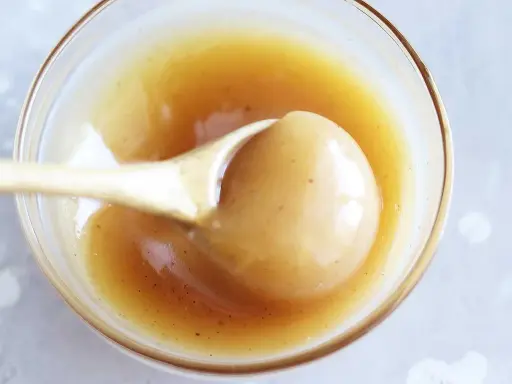 En sked lyfter krämig kolasås ur en skål. Perfekt för ditt kolasås recept!
