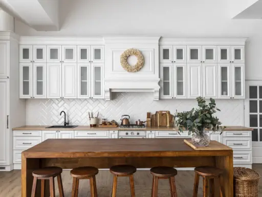 Cuisine lumineuse avec des armoires blanches et un îlot en bois massif. On dirait qu'on a réussi à faire une cuisine avec des vieux meubles, le tout dans un style rustique chic.