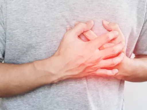Dłoń na klatce piersiowej, odczuwając niepokojące kołatanie serca w nocy.