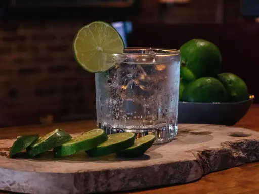 Erfrischender Gin Tonic mit Eis, Limettenscheiben und einer Schale voller Limetten. Perfekt für einen warmen Abend.