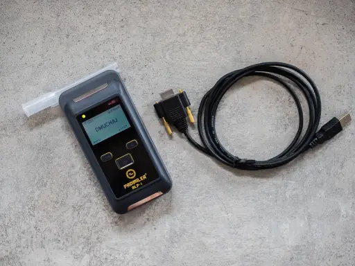 Alkomat z ustnikiem i kablem USB na szarym tle.