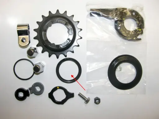 Zestaw części do naprawy przerzutki w piaście: zębatka, nakrętki, uszczelki, mechanizm i śruba.