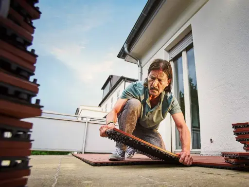 Man bygger trall på balkong. Staplar med trallplattor syns till vänster.