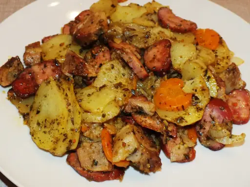 Pyszne duszonki z piekarnika: ziemniaki, kiełbasa i marchewka, doprawione ziołami.