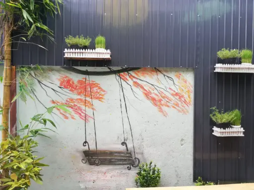 Un columpio pintado en un muro, ideal para inspirar al pintar patios pequeños. Las ramas anaranjadas y el bambú añaden color.
