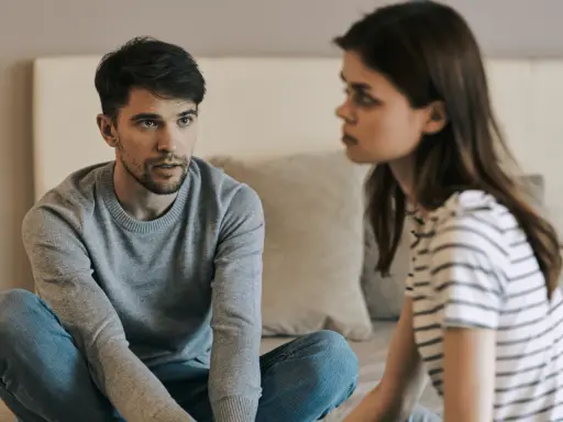 Un homme et une femme se regardent, assis sur un lit, dans une ambiance tendue.