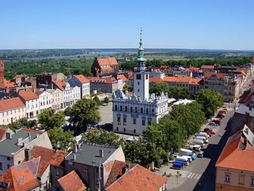 Urokliwy widok na rynek i zabytkowe kamieniczki w kujawsko-pomorskim. W tle rzeka i zieleń.