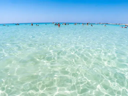 Acque cristalline e turchesi bagnano le spiagge di Lecce, dove bagnanti si godono il sole e il mare limpido.
