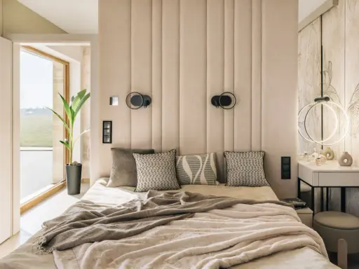 Miękka, pikowana **ściana za łóżkiem w sypialni** tworzy przytulną atmosferę. Dwa kinkietowe oświetlenie dodają elegancji.