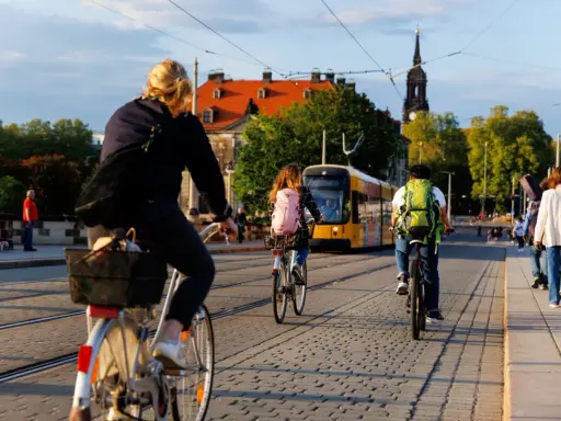 Menschen radeln durch eine Stadt in Deutschland, ein gelber Tram fährt vorbei. Perfekt für Bikepacking Deutschland!