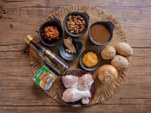 Zutaten für ein Massaman Curry Paste Rezept: Hähnchenschenkel, Kokosmilch, Erdnüsse, Kartoffeln, Zwiebel, Fischsauce, Currypaste und Gewürze.