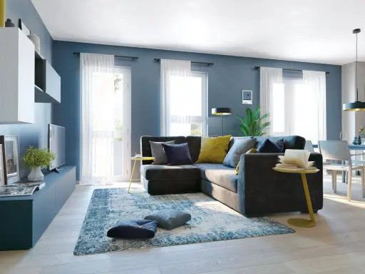 Un soggiorno moderno con divano angolare grigio scuro, cuscini blu e gialli, tappeto blu e bianco. Le pareti blu creano un'atmosfera rilassante, dimostrando che blu e grigio stanno bene insieme.