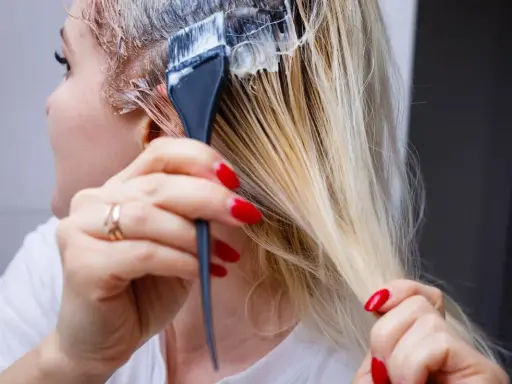 Application d'une patine sur des cheveux blonds. Le dosage précis est essentiel pour obtenir la teinte désirée.