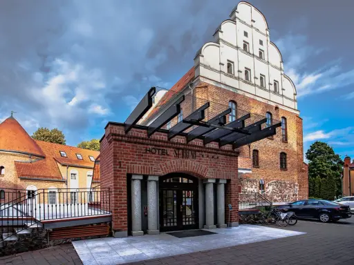 Hotel St. Bruno w Giżycku, dawniej zamek krzyżacki, z charakterystyczną ceglaną fasadą i białym szczytem.