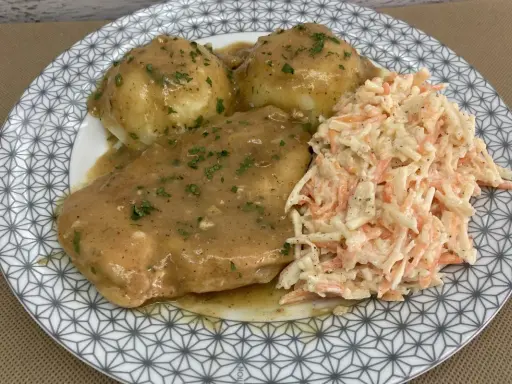 Pyszna pierś z kurczaka w sosie własnym, podana z purée ziemniaczanym i surówką z marchewki i kapusty.