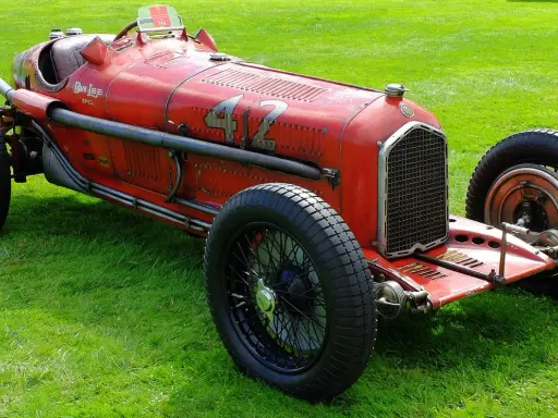 Roter Alfa Romeo P3 Rennwagen mit Nummer 42 fährt auf einer Straße, Fahrer mit Kopftuch.