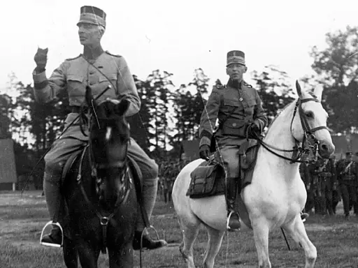 Två militärer till häst, kanske under en övning för regementen i Sverige. Bakom syns fler soldater och träd.