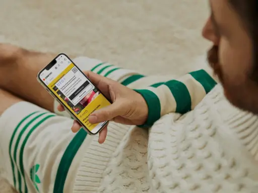 Mężczyzna sprawdza na telefonie, czy zalando jest legit, przeglądając aplikację z poradami stylistycznymi.