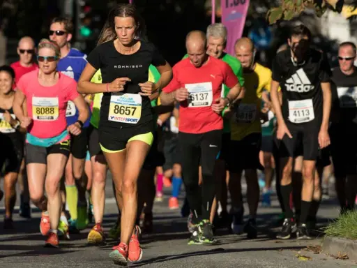 Löpare i Stockholm Halvmarathon kämpar för ett rekord. En kvinna med nummer 8657 leder loppet.