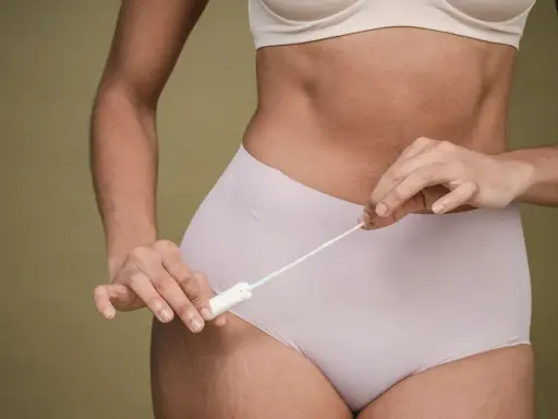 Kobieta trzymająca tampon, zastanawiająca się, czy okres się spóźnia.