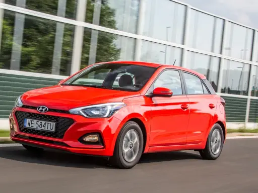 Czerwony Hyundai i20 1.2 benzyna w ruchu, z nowoczesną atrapą chłodnicy i światłami.