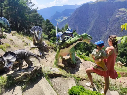 Una familia disfruta de un día prehistórico con dinosaurios en Andorra con niños. Las montañas de fondo crean un paisaje espectacular.