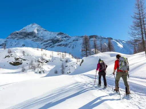 Coppia con ciaspole esplora un sentiero innevato in montagna, un'ottima idea per chi cerca dove ciaspolare in Lombardia.
