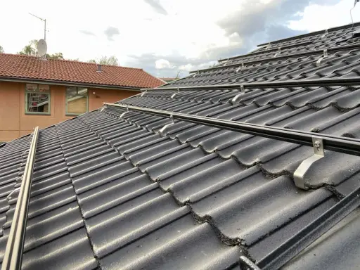 Solpaneler monteras på taket med hjälp av robusta aluminium skenor. Takpannorna är mörka och vågformade.