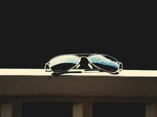 Okulary przeciwsłoneczne typu aviator leżące na drewnianej powierzchni.