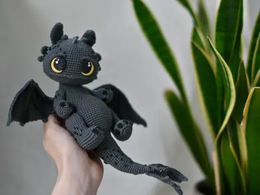 Adorable dragón amigurumi gris con ojos amarillos brillantes. ¡Encuentra el dragon amigurumi patron gratis en español para crear el tuyo!