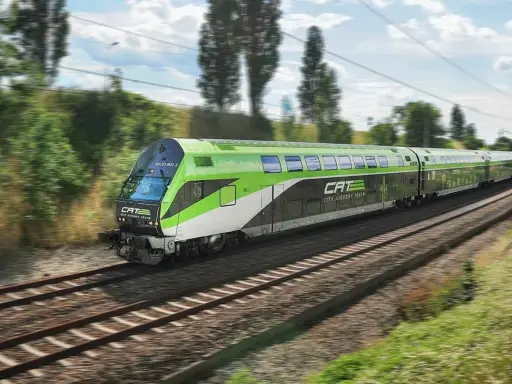 Grön och vit CAT City Airport Train susar fram på spåret, på väg till flygplatsen i Wien.