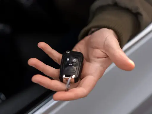 Mano sosteniendo una llave de coche moderna, lista para codificar y arrancar.