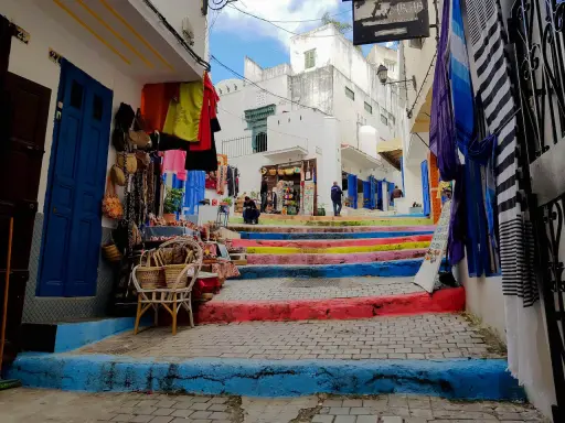 Bunte Treppe in Tanger, wo Frauen in bunten Gewändern Souvenirs verkaufen.