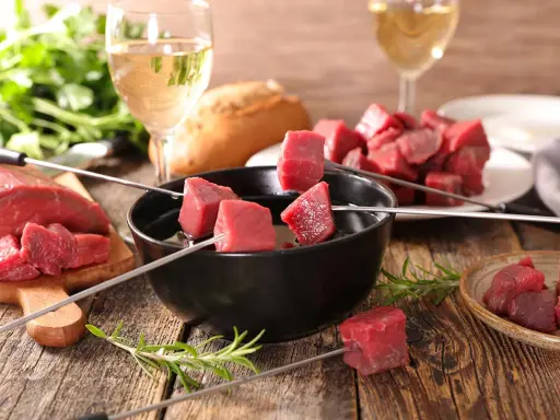 Préparation pour comment faire une fondue bourguignonne : dés de bœuf sur des brochettes, prêts à être plongés dans l'huile chaude.