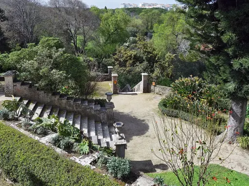 Steintreppen und üppige Vegetation in einem botanischen Garten mit Blick auf Lissabon.