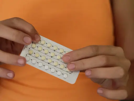 Manos sostienen un blíster de pastillas anticonceptivas. Me he quitado el anillo y no me baja la regla, ¿será por esto?